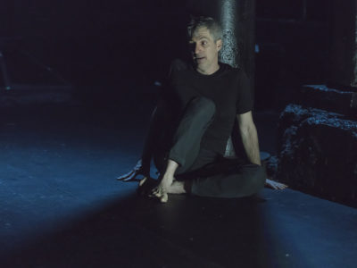 An actor in a scene: a distressed man in the sitting on the floor in the dark