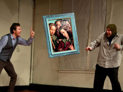 Two actors on stage: Two men arguing in front of a suspended fake medieval painting